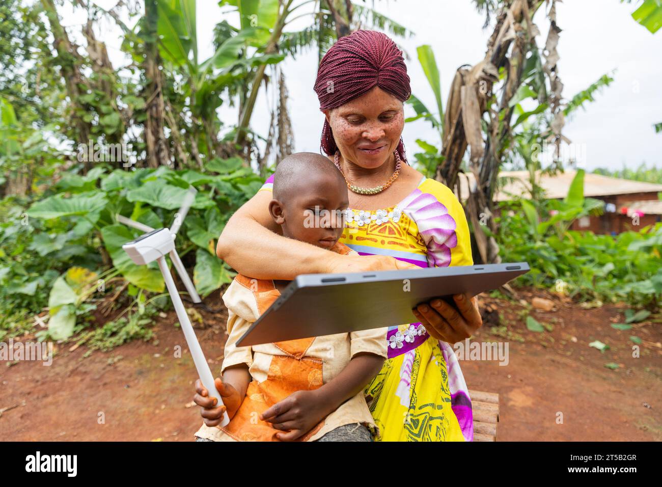 African albino mother with the help of tablet lectures her child on solar energy. Stock Photo