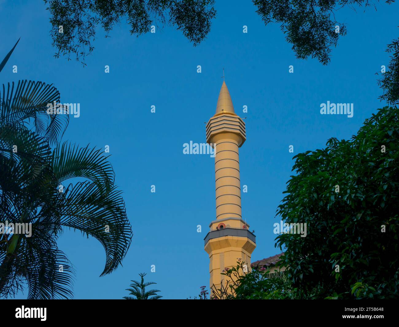 Tower of Universitas Gadjah Mada mosque (Masjid Kampus UGM), with blue sky and palm leaves background. Stock Photo