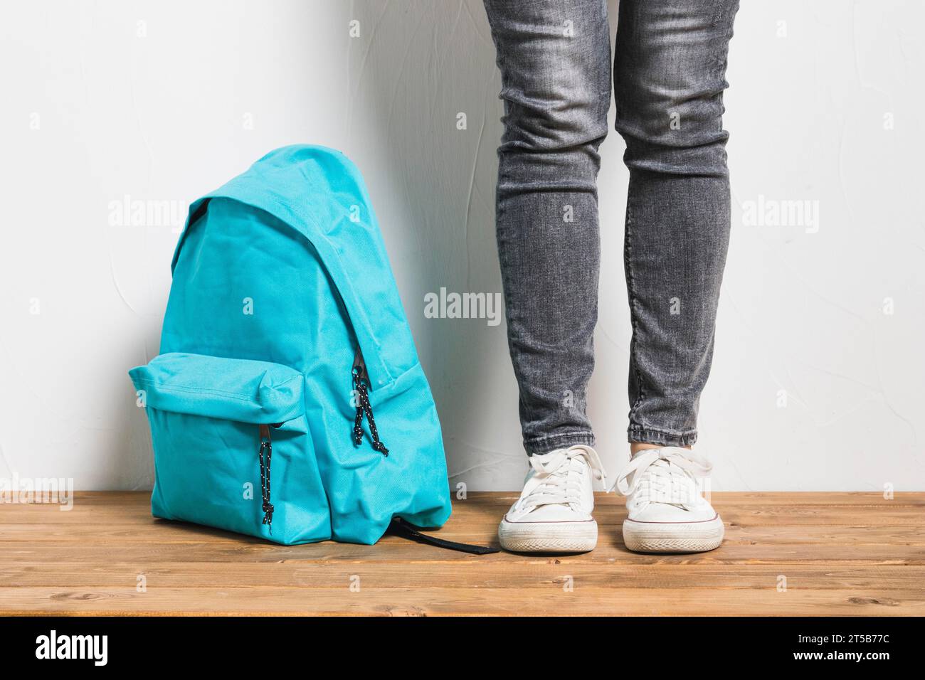 Faceless person standing beside schoolbag wooden table Stock Photo