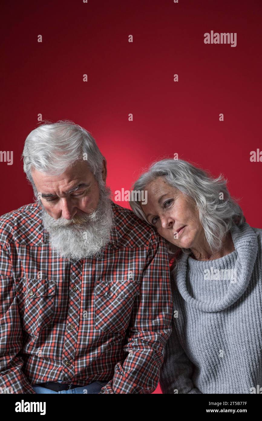 Depressed senior couple against colored background Stock Photo