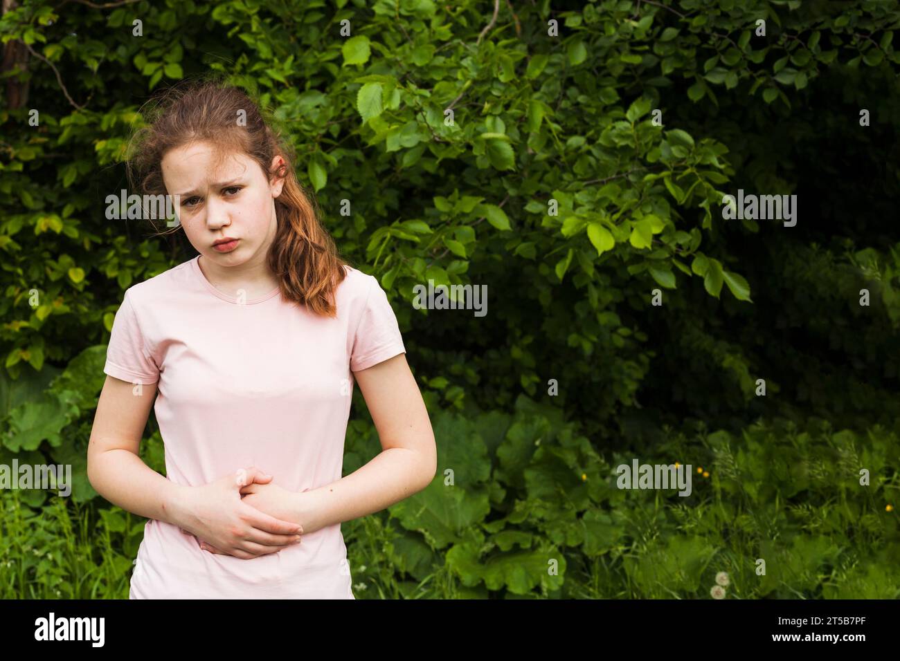 Innocent girl holding her stomach while having stomach pain park Stock Photo