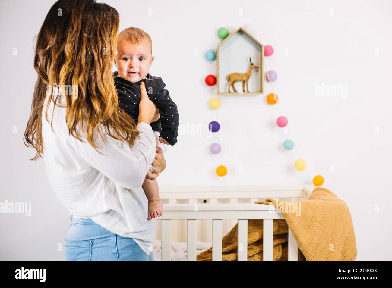 Mother holding baby near cradle Stock Photo Alamy
