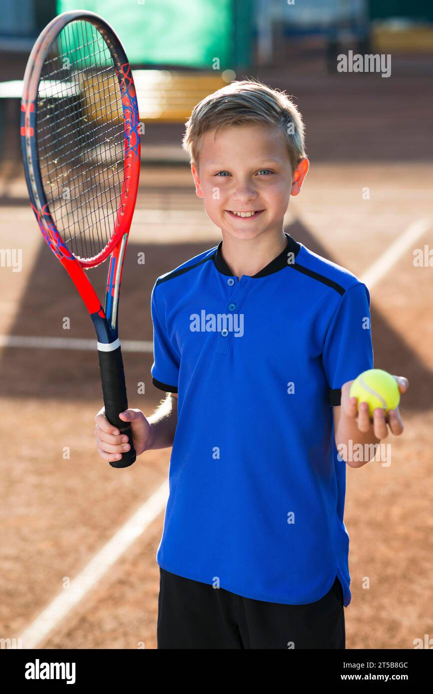 Smiley kid holding tennis racket ball Stock Photo