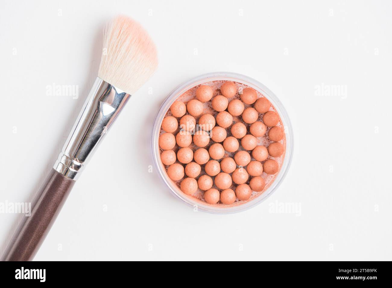 Bronzing pearls with makeup brush white background Stock Photo Alamy