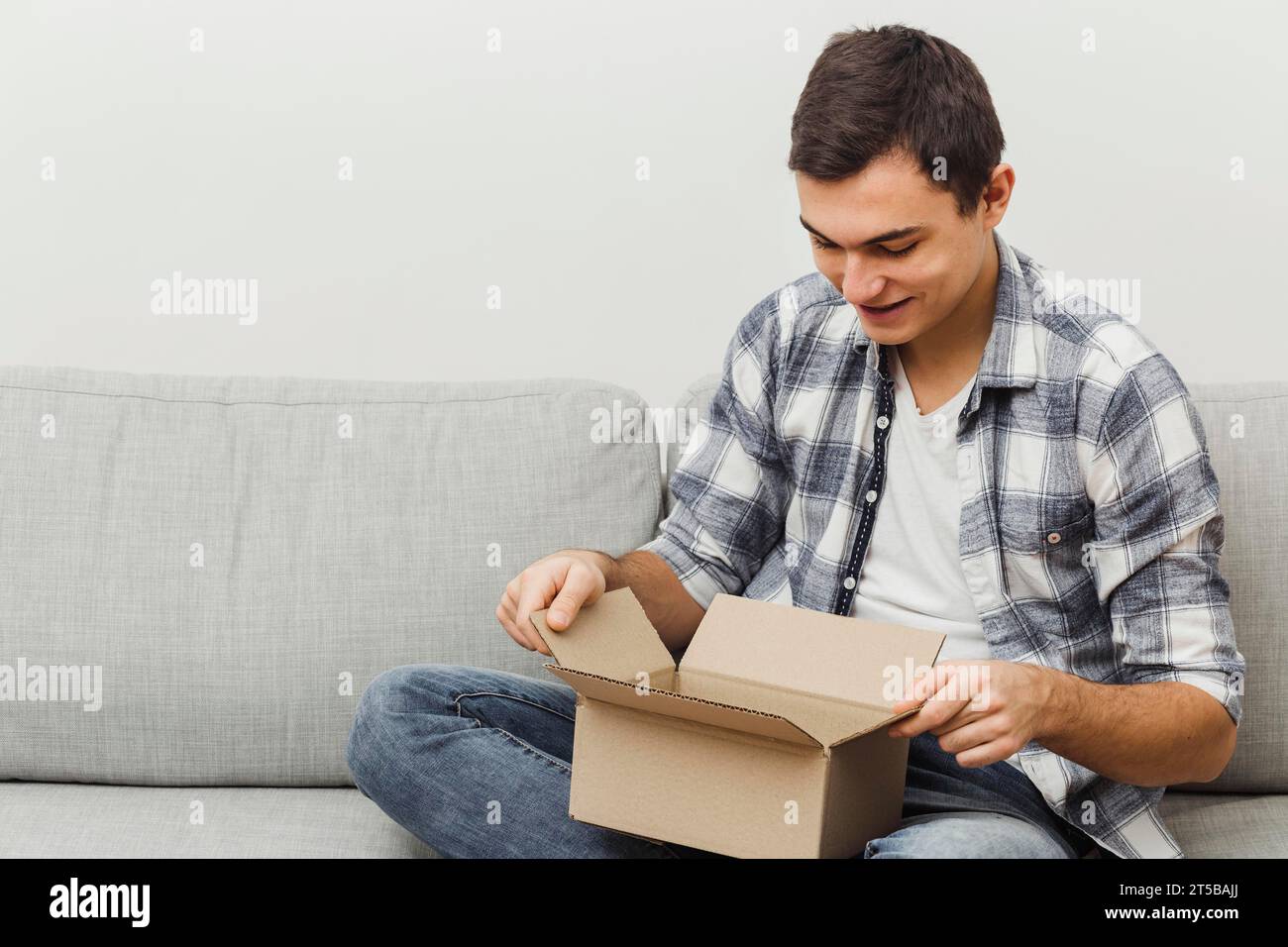 High angle man couch opening box Stock Photo