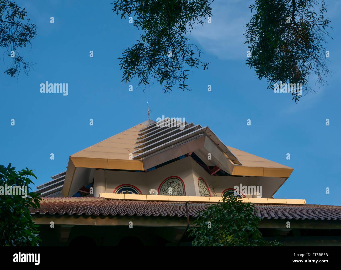 The roof top of niversitas Gadjah Mada mosque (Masjid Kampus UGM), with blue sky and palm leaves background. Stock Photo