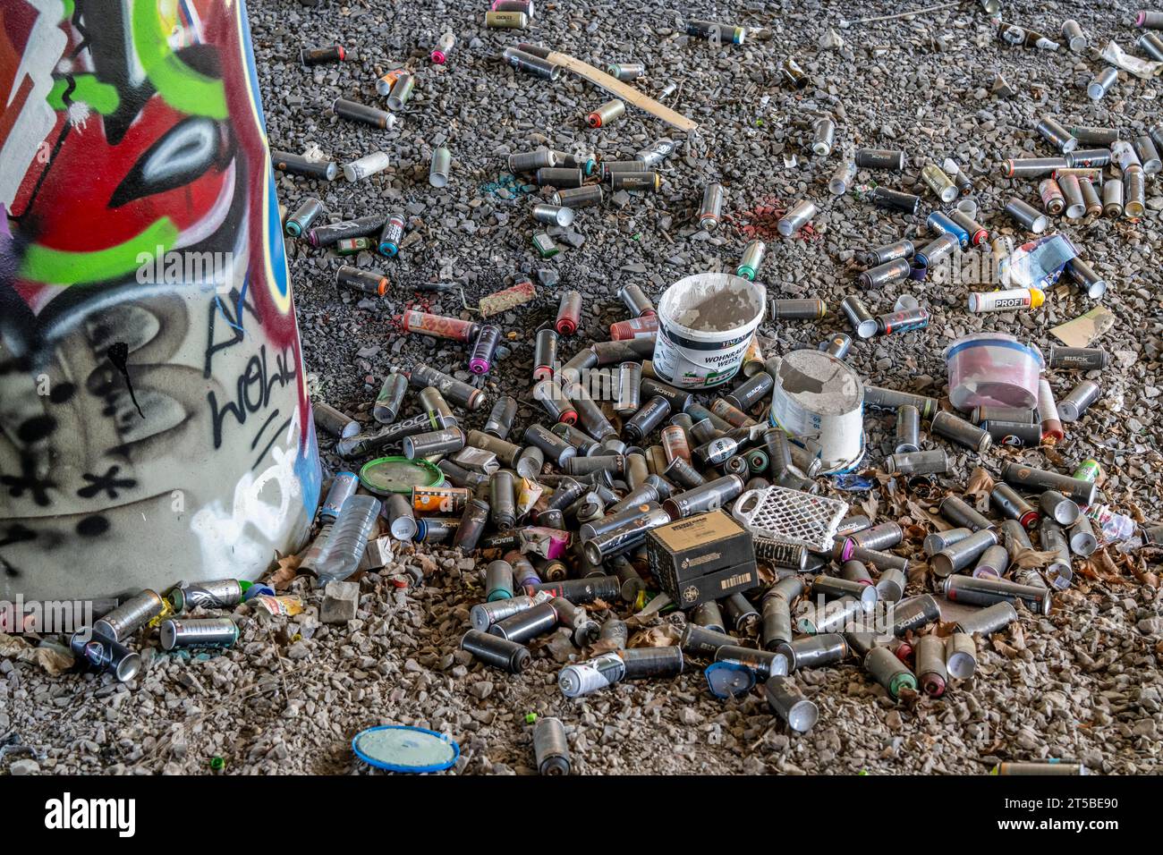 Empty spray paint cans, on a railway track below a road bridge, thrown