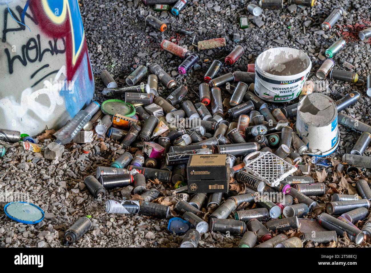 Empty spray paint cans, on a railway track below a road bridge, thrown