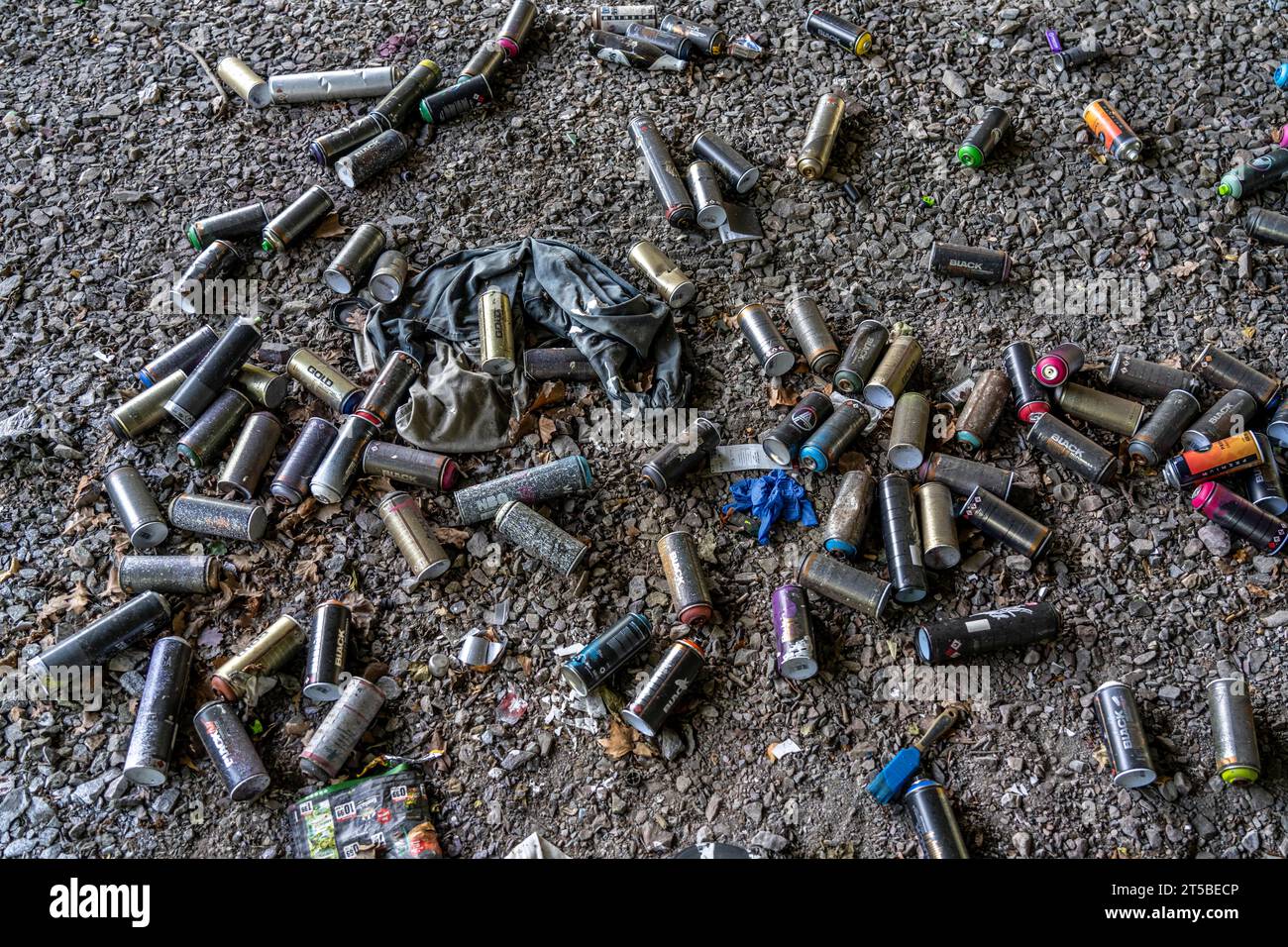 Empty spray paint cans, on a railway track below a road bridge, thrown