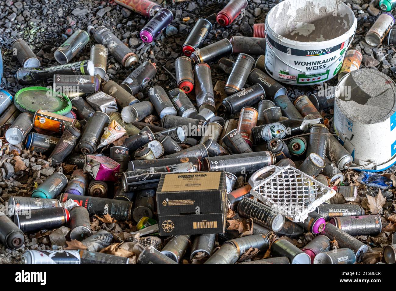 Empty spray paint cans, on a railway track below a road bridge, thrown