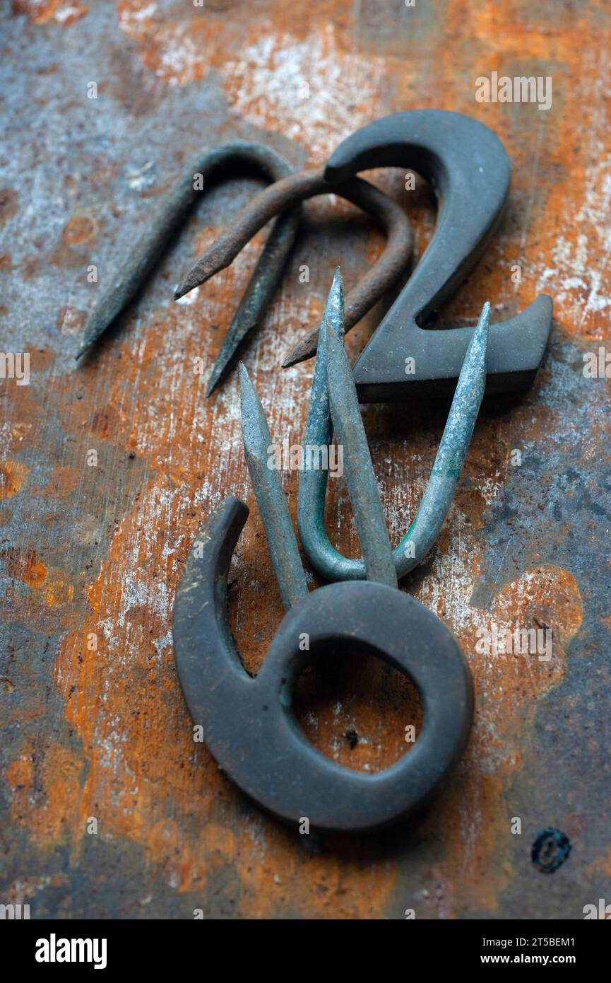 rusting tin and staples together with patinated brass house numbers ellingham norfolk england Stock Photo