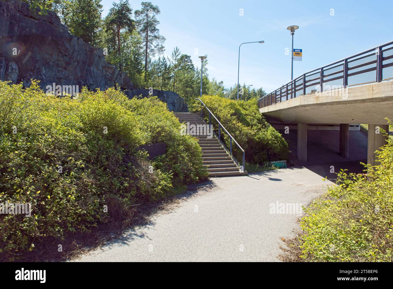 Asphalt coated walkway going under concrete bridge in sunny summer weather. Stock Photo