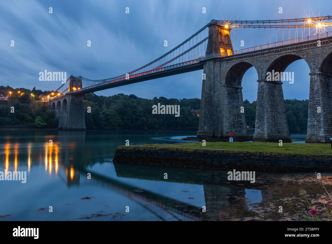 The iconic Menai Bridge, a suspension bridge designed by Thomas Telford and built in the 19th century. The bridge spans the Menai Strait, connecting m Stock Photo