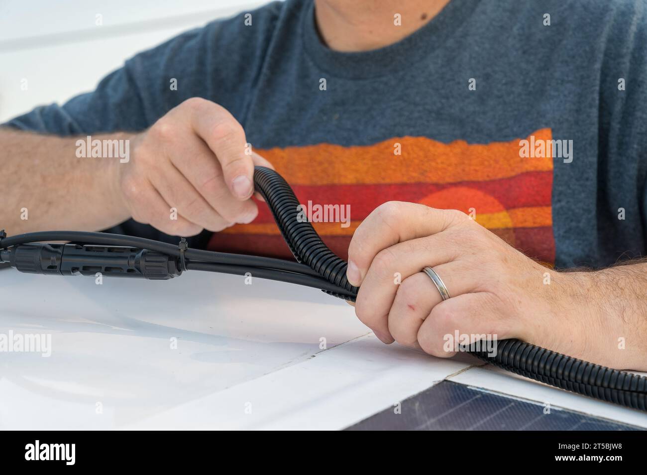 Man installing a split wire loom conduit for a solar panel wire