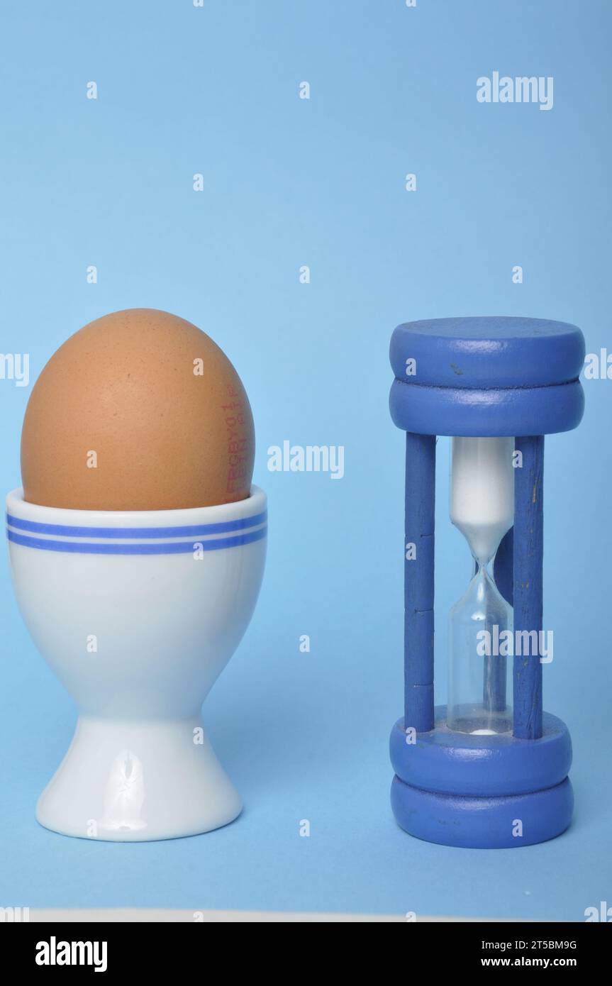Boiled egg and hourglass on a blue background Stock Photo