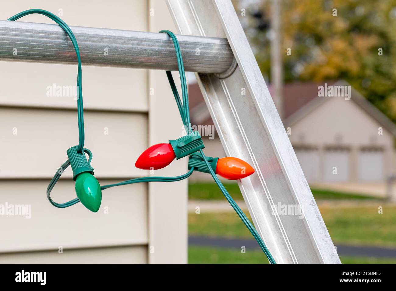 Christmas string lights hanging on ladder rung outside of house