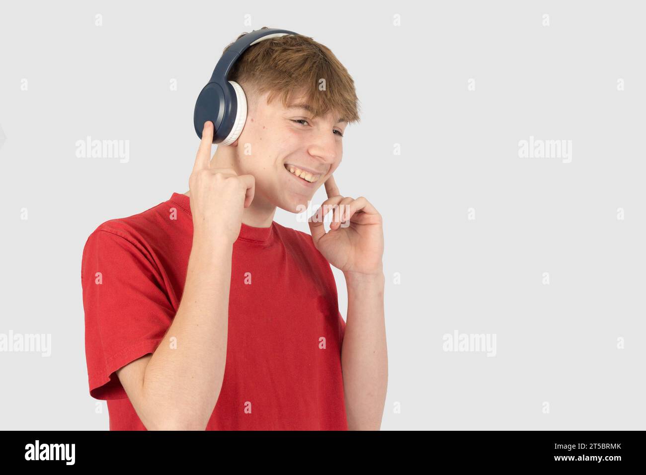 Caucasian 15 year old teenage boy, wearing a red tshirt, listening to