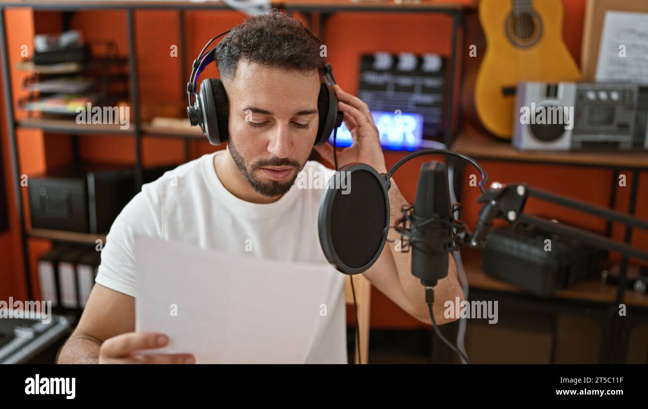 Young arab man musician wearing headphones singing song at music studio ...