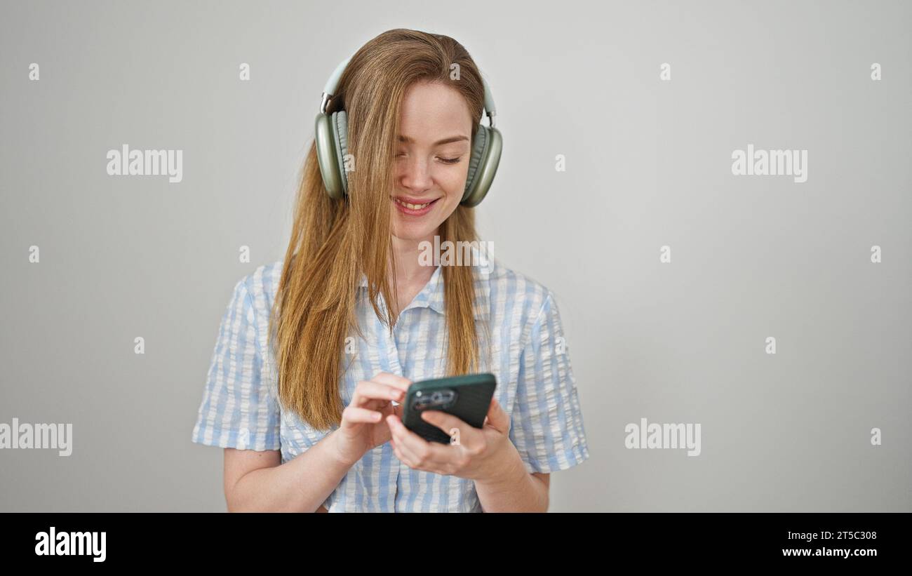 Young blonde woman listening to music using headphones and smartphone ...