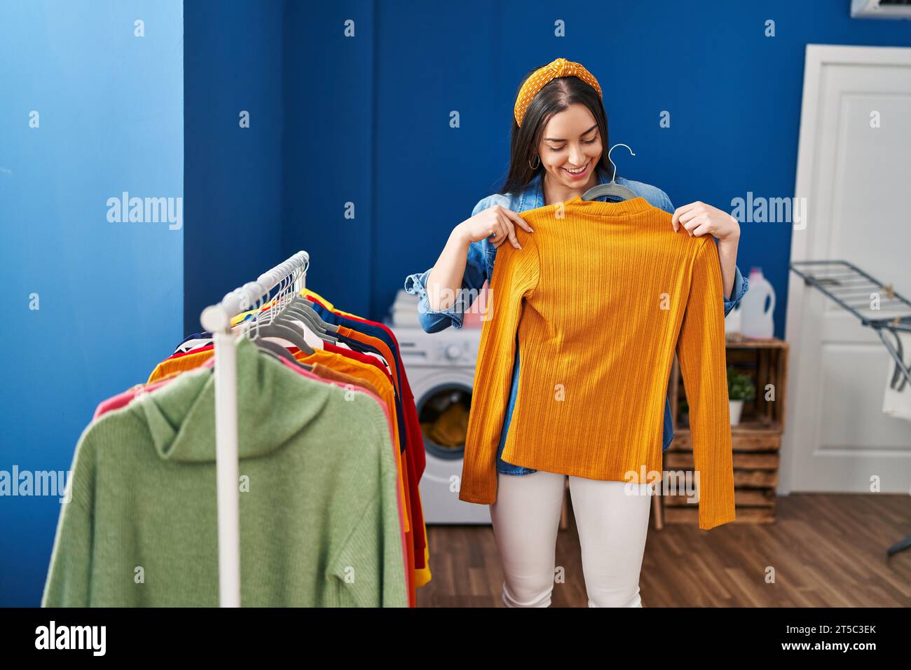 Hispanic Rack Young beautiful hispanic woman holding clothes on rack at laundry room ...