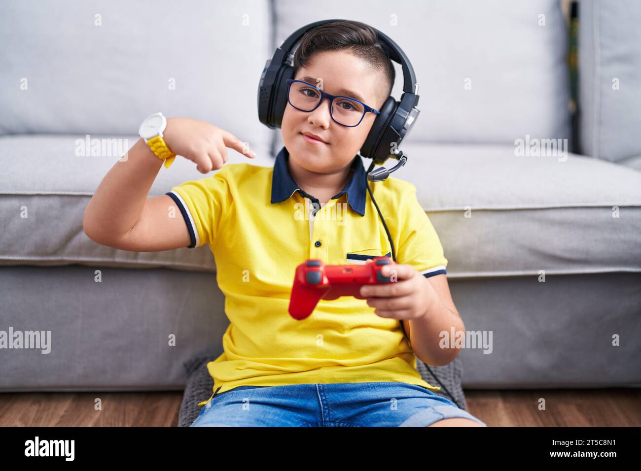 Kid Using Controller Young hispanic kid playing video game holding controller wearing ...