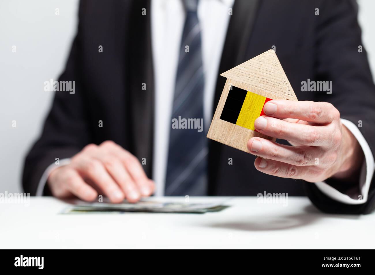 Businessman hand holding wooden Home model with Belgian flag. insurance and property concepts Stock Photo