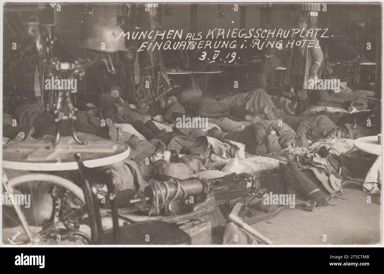 'München als Kriegsschauplatz. Einquartierung i Ring Hotel, 3.5.19' / 'Munich as a theatre of war. Accommodation in the Ring Hotel, 3.5.19': Members of the paramilitary Freikorps billeted in the dining room of a Munich hotel during the attack on the Bavarian Soviet Republic in May 1919. The men are sleeping on the floor and a machine gun can be seen in the foreground. A German helmet is balanced on a candelabra on a table. Stock Photo