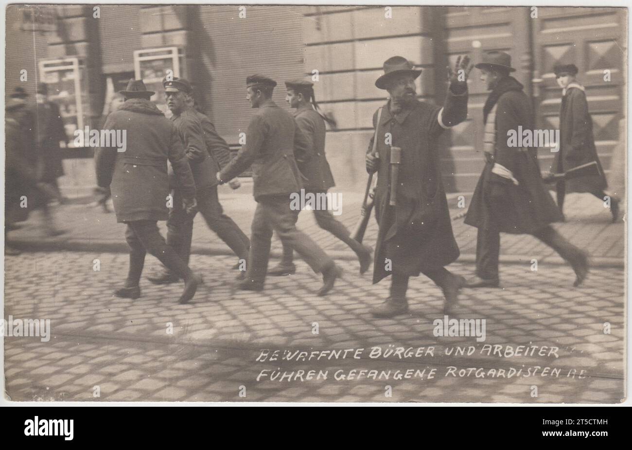 'Armed citizens and workers drove away captured Red Guards' / 'Bewaffnete bürger und arbeiter fuhren gefangene rotgardisten': aftermath of street fighting during the German revolution, 1918-1919, after the First World War. The location of the photograph is unidentified but it may show Munich during the overthrow of the Bavarian Soviet Republic. Communist Red Guards being led away by armed men in civilian clothes. One armed man is gesturing to someone out of camera shot. Stock Photo