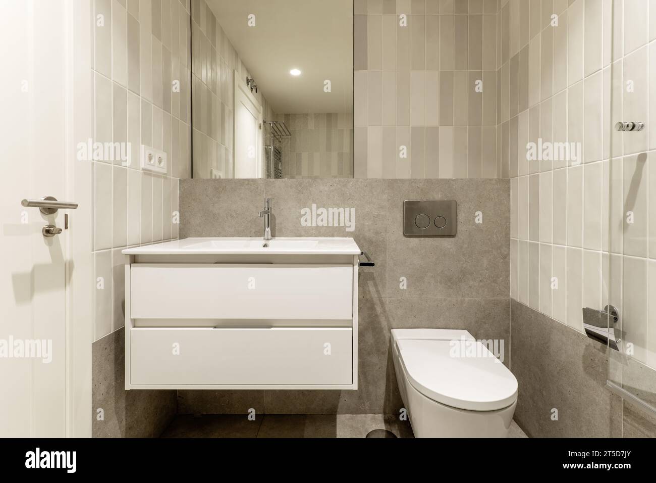 Frontal image of small modern bathroom with gray stone-like tiles Stock Photo