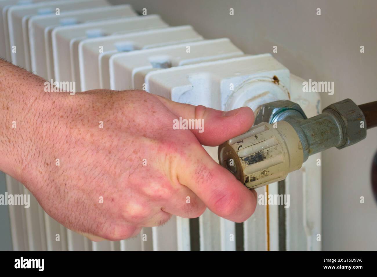 Hand closing the valve of a hot water radiator. Energy conservation