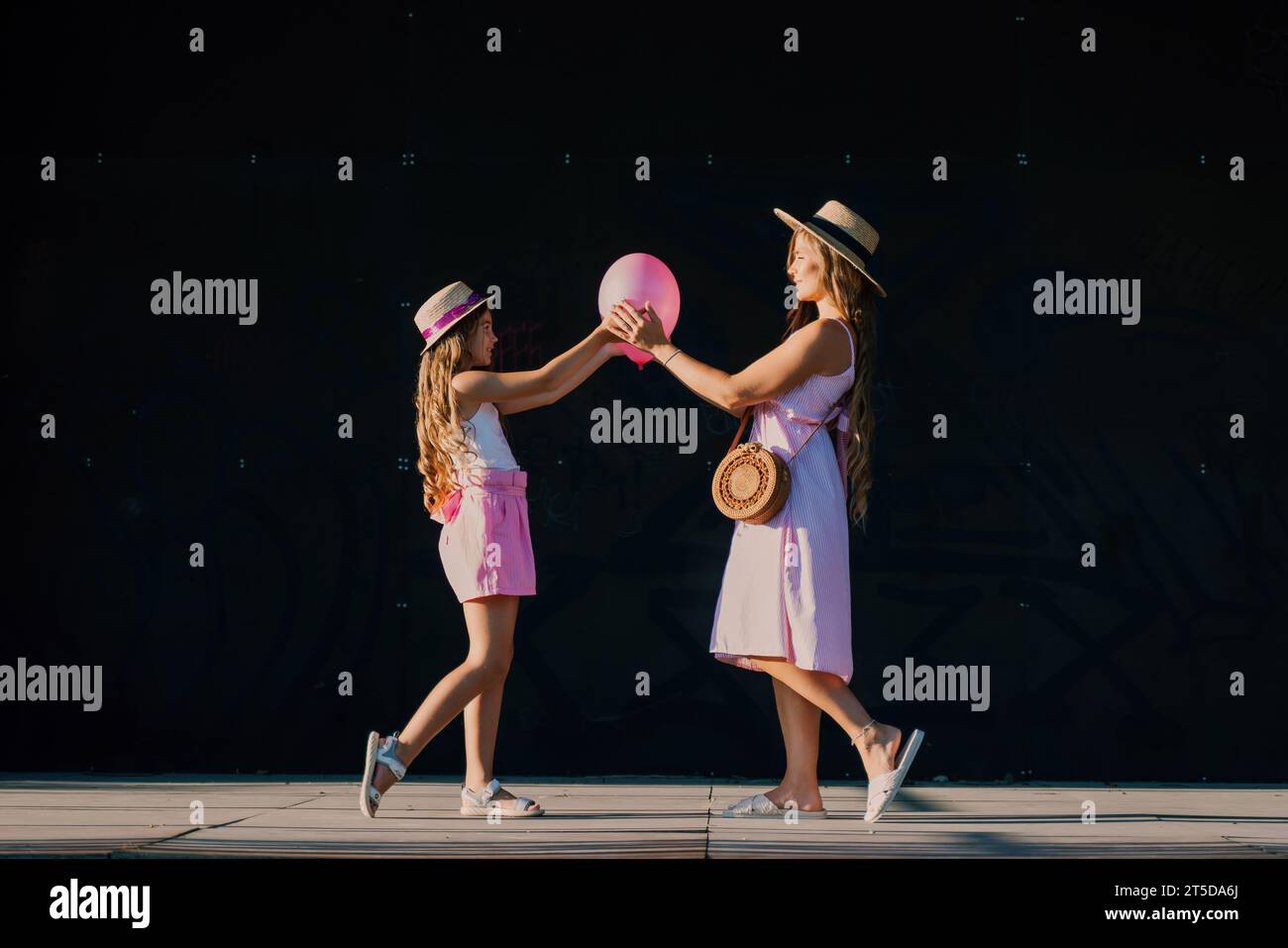 mother and daughter stand in pink dresses with flowing long hair on a ...