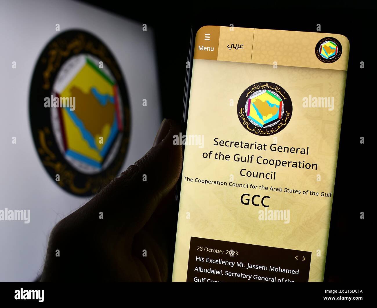 Person holding cellphone with webpage of Arab union Gulf Cooperation Council (GCC) in front of logo. Focus on center of phone display. Stock Photo