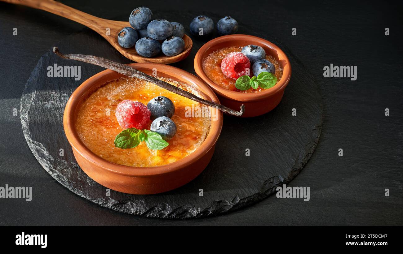 Cremon Raspberry Brulee Creme brulee with raspberry, blueberry and mint leaves on dark slate ...