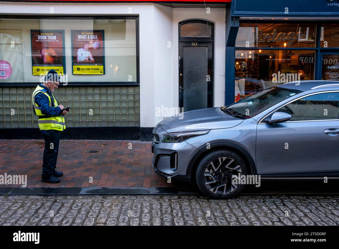 A Traffic Warden Taking Details Of An Illegally Parked Car, High Street, Lewes, East Sussex, UK Stock Photo