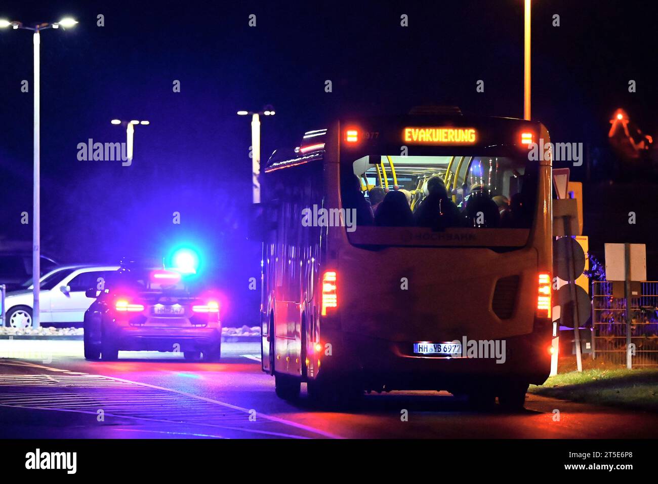 Hamburg, Germany. 04th Nov, 2023. A police car with its blue lights on escorts a bus full of people on the 'Evacuation' sign at the airport. Hamburg Airport has been closed after a vehicle entered the premises. A gunman had broken through a gate with his vehicle and had already fired twice into the air, a spokesman for the federal police said on Saturday evening. Credit: Jonas Walzberg/dpa/Alamy Live News Stock Photo