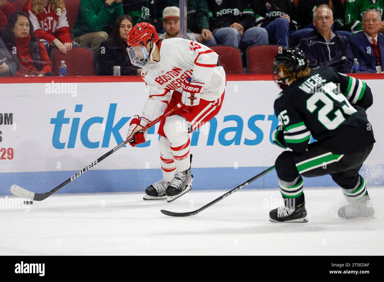 Boston University forward Dylan Peterson (13) keeps the puck away from