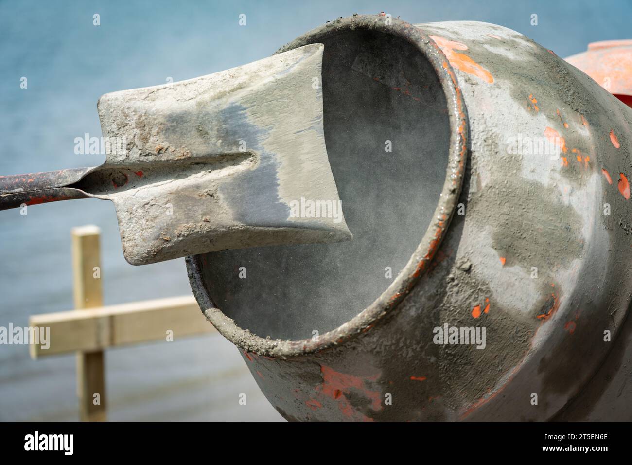 Focus on inside concrete mixer turning blurred in motion with shovel raised in process of mixing