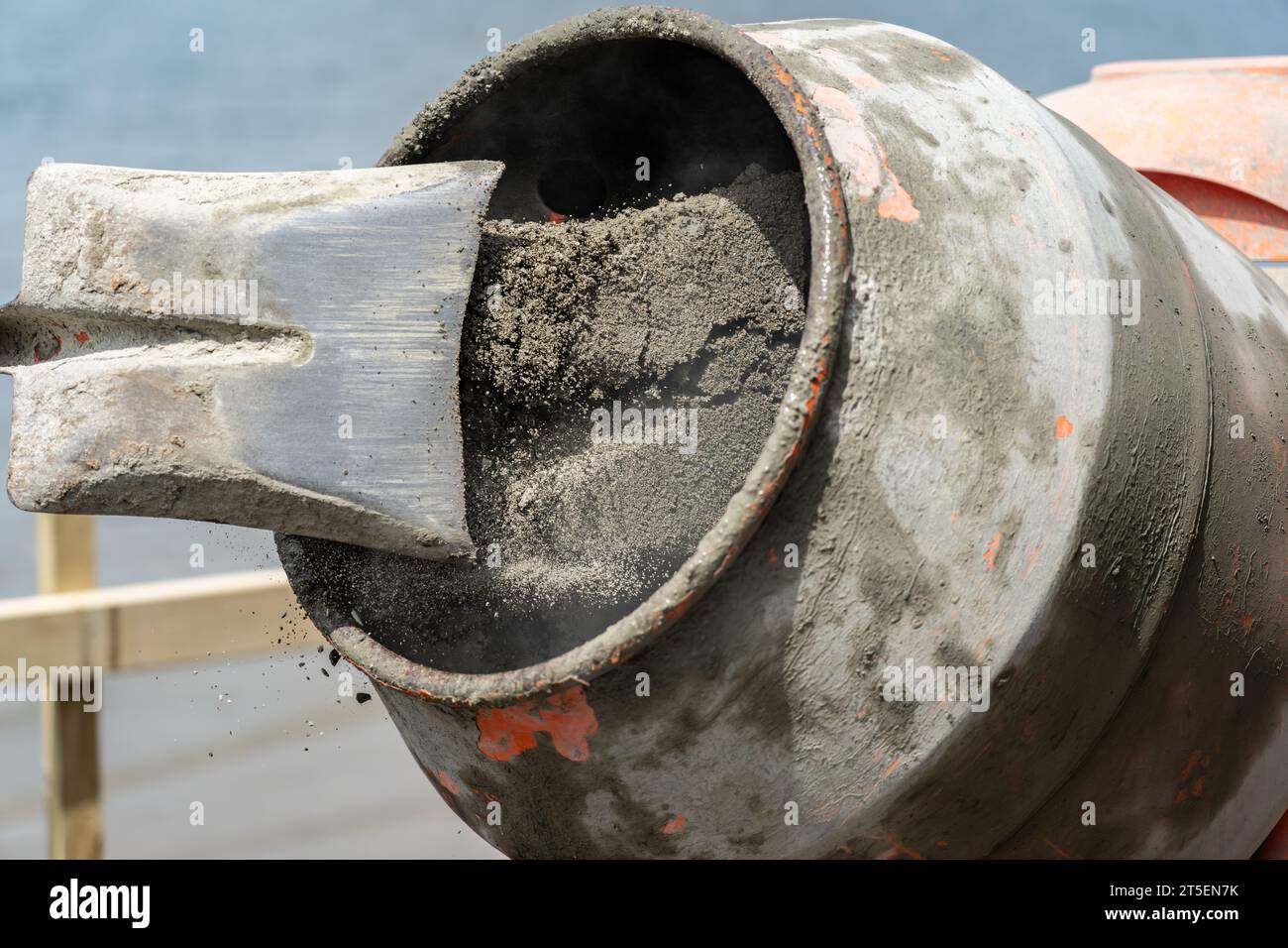 focus-on-grit-and-sand-inside-concrete-mixer-turning-blurred-in-motion-as-sand-leaves-raised-shovel-2T5EN7K.jpg
