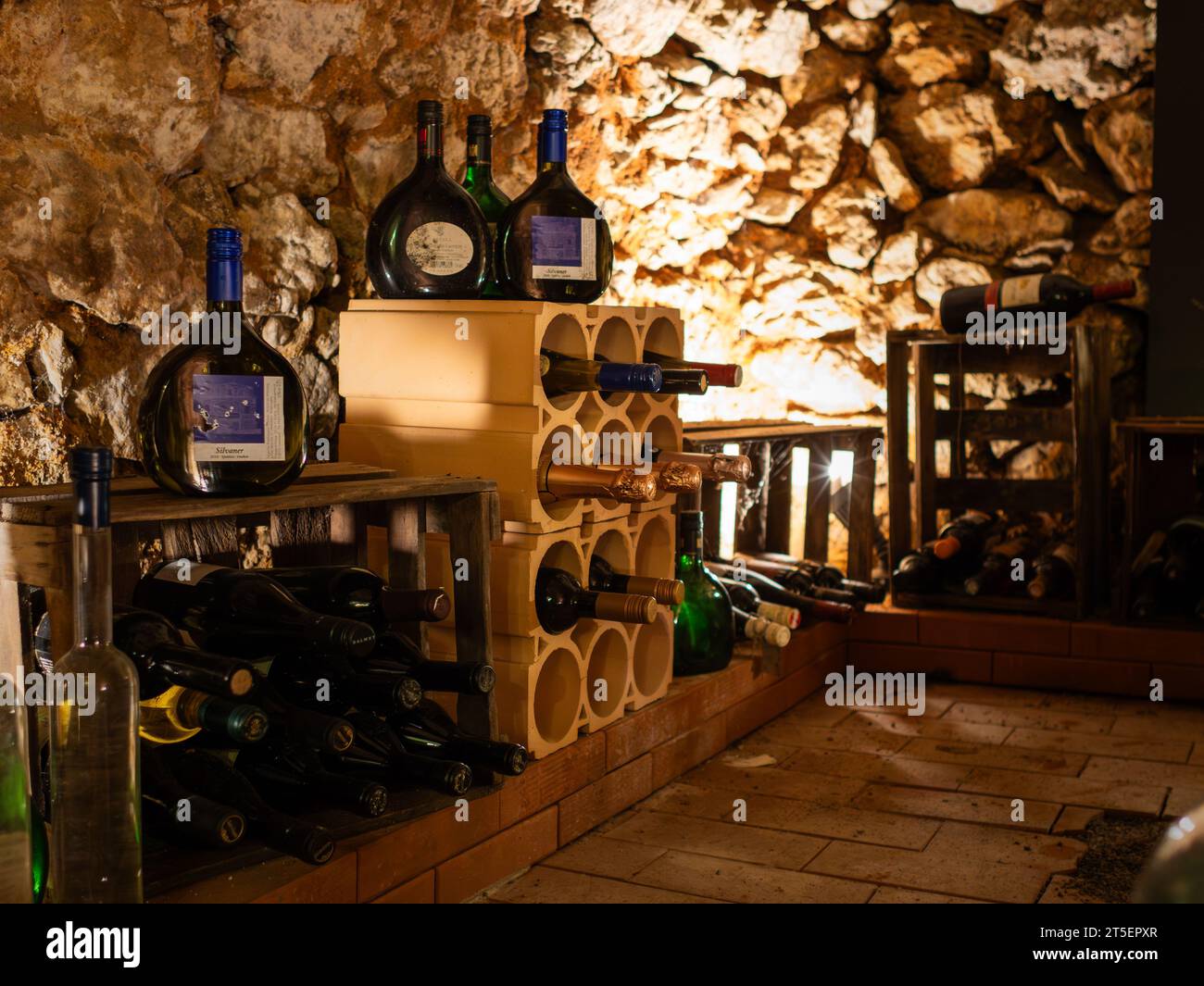 Small wine cellar in an old house basement. Different bottles are stored in a room. Shelves are full of alcoholic beverages. Gourmet lifestyle at home Stock Photo