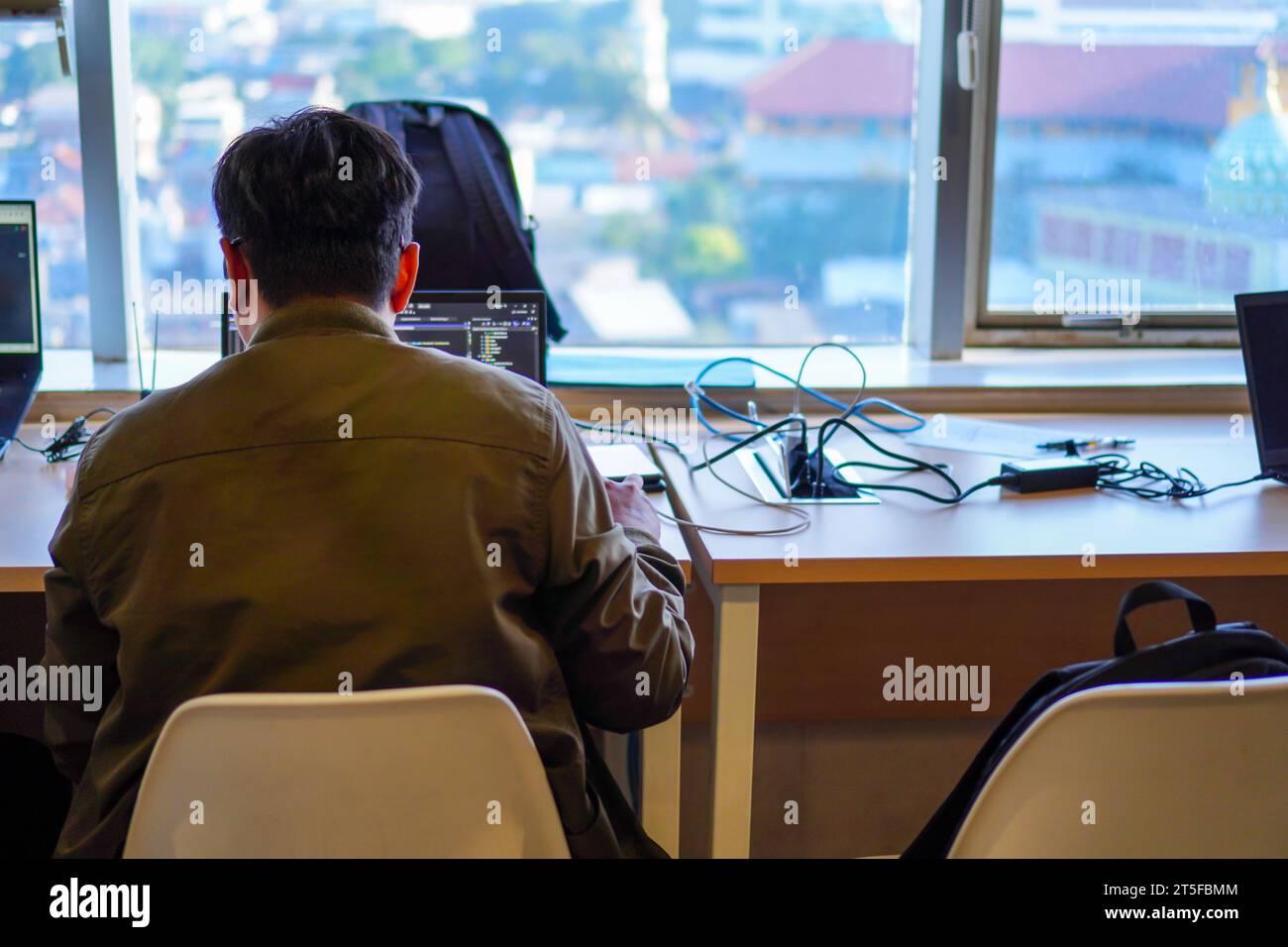 Back view of IT system developer busy working with computer system ...