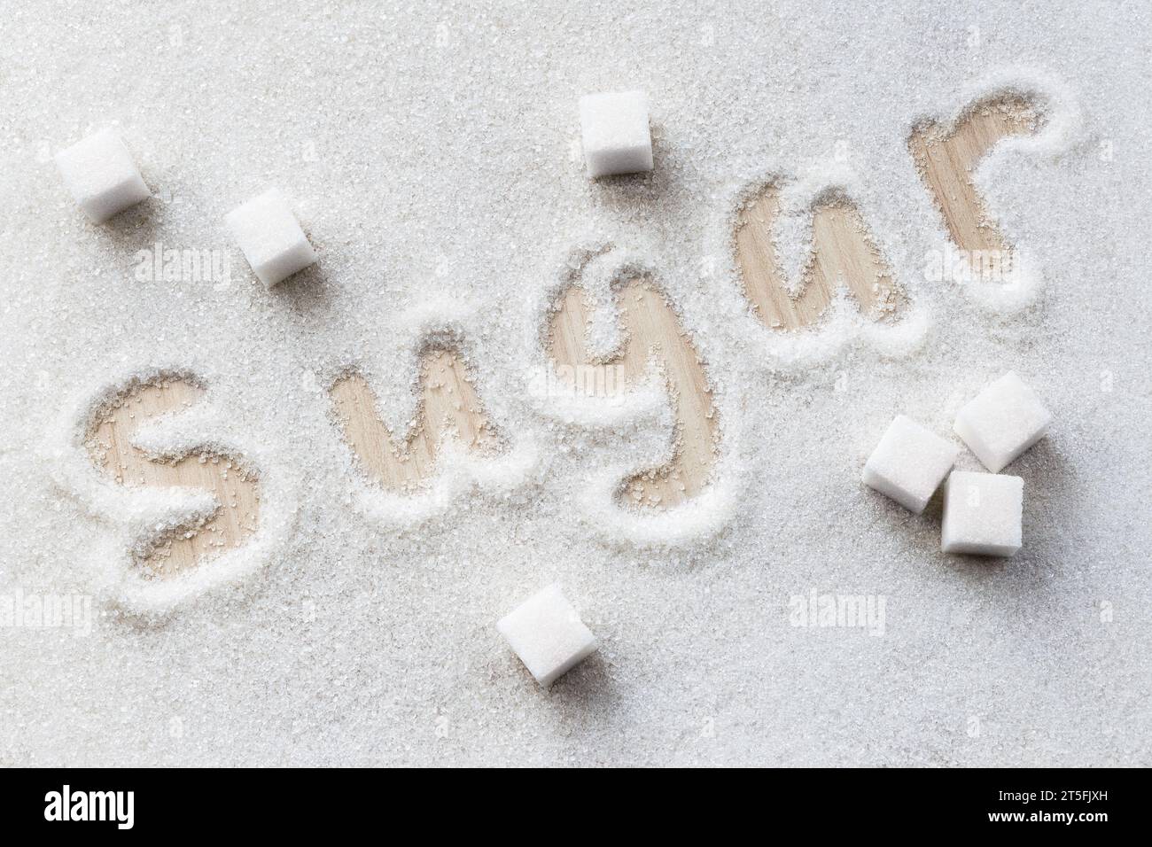 The inscription "Sugar" on granulated sugar. Refined sugar cubes. Stock Photo