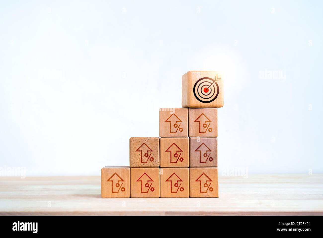 Target icon on wooden cube blocks on top of bar graph chart steps with