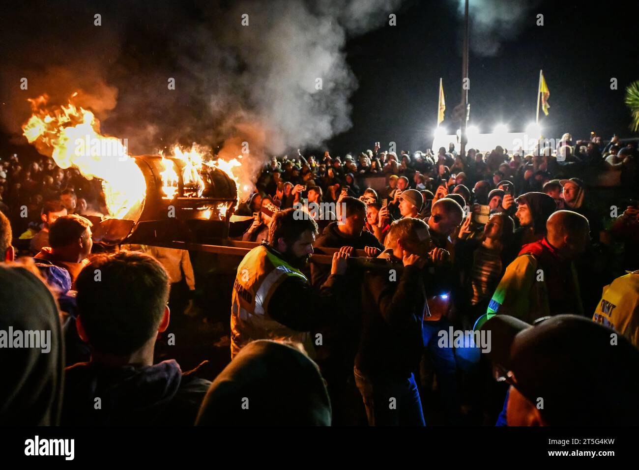 Ottery St Mary, UK. Saturday 4 November 2023. Locals take part in the Ottery St Mary Burning Tar Barrels. Running with burning barrels through the streets of Ottery St Mary in Devon in a traditional event stretching back hundreds of years. Credit: Thomas Faull/Alamy Live News Stock Photo