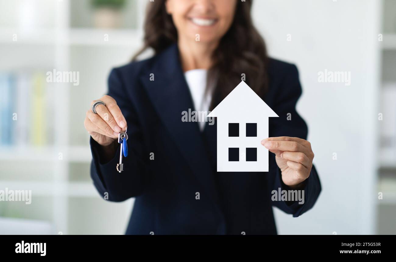 Real estate agent holding home key and model of house Stock Photo - Alamy