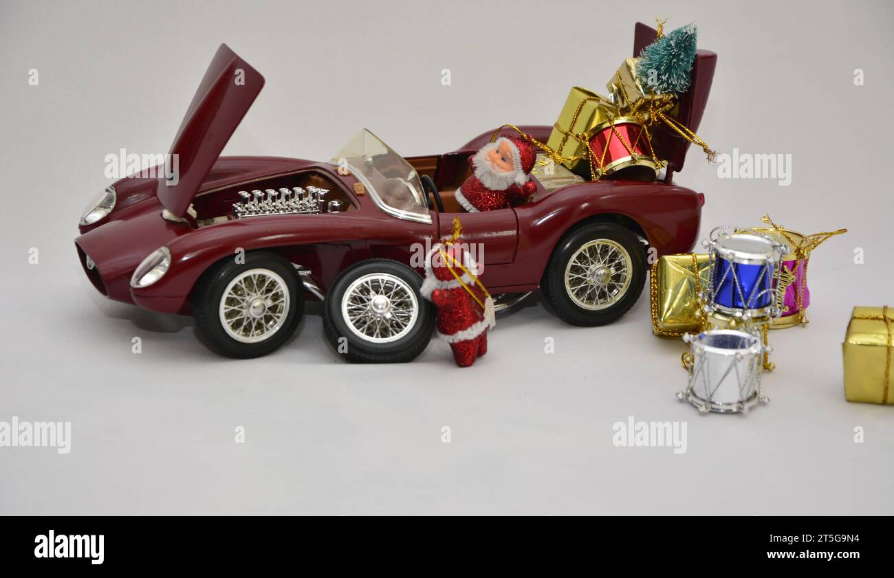 Santa Claus putting gifts in the red sports car and checking the engine and tires. Selective focus. Brazil, South America Stock Photo