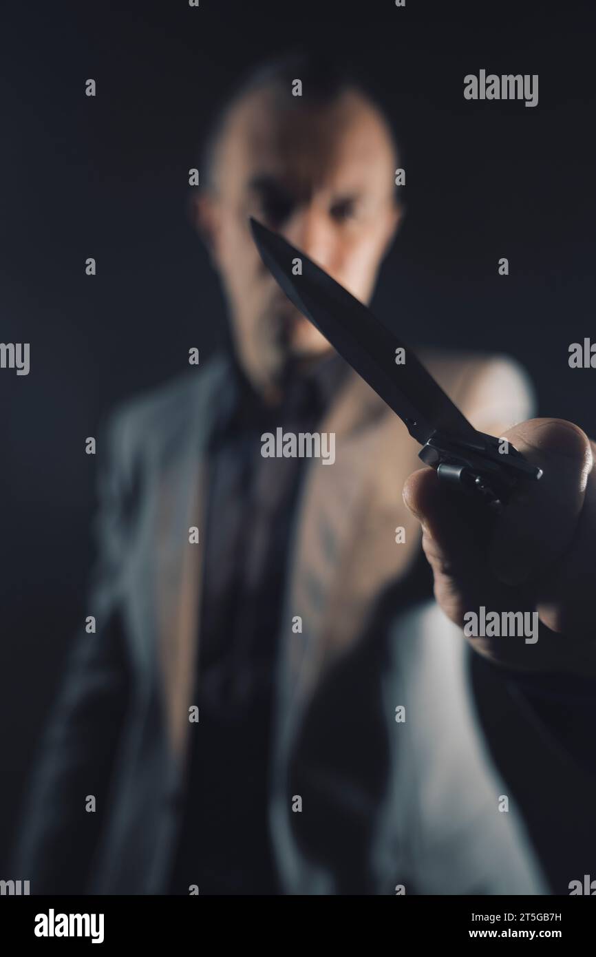 Assassin murderer killer holding knife bladed weapon in dark scary photo book cover design. Stock Photo