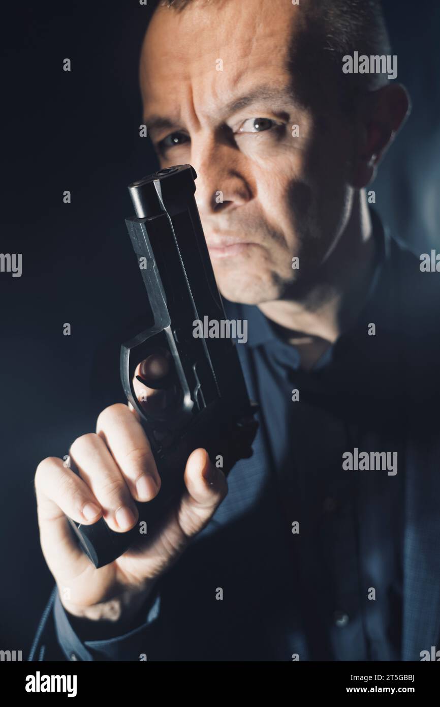 Spy thriller mafia boss assasin portrait photo in suit holding pistol gun. Stock Photo