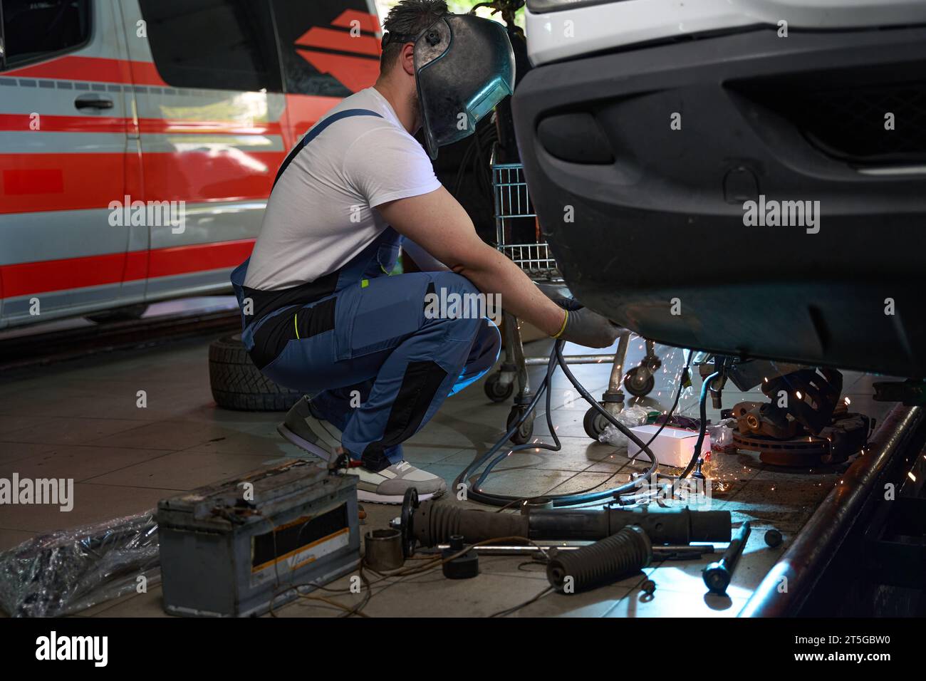 Skilled mechanic performing client automobile repair in workshop Stock Photo