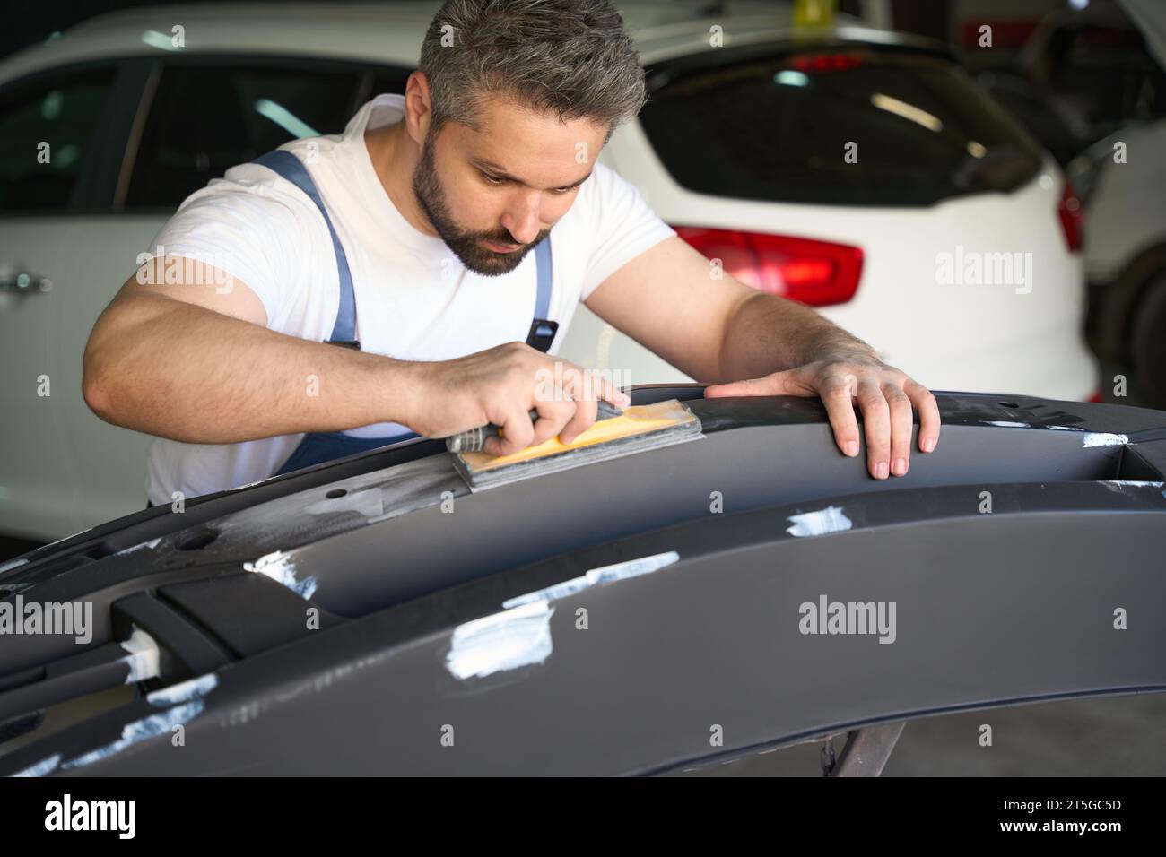 Experienced car detailer buffing automotive body part Stock Photo