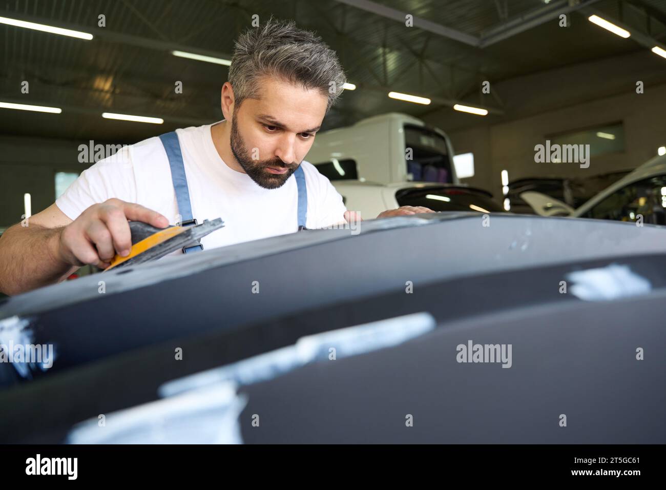 Professional automotive detailer polishing car body part with tool Stock Photo